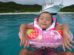 ケラマの綺麗な海で浮き輪で泳ぐ子供